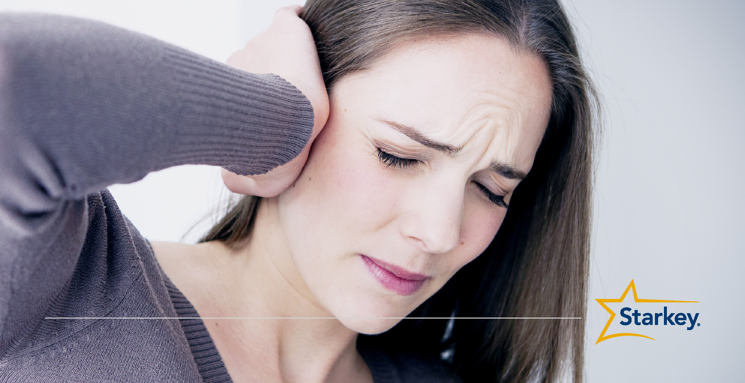 Woman pressing her right hand against her right ear in pain